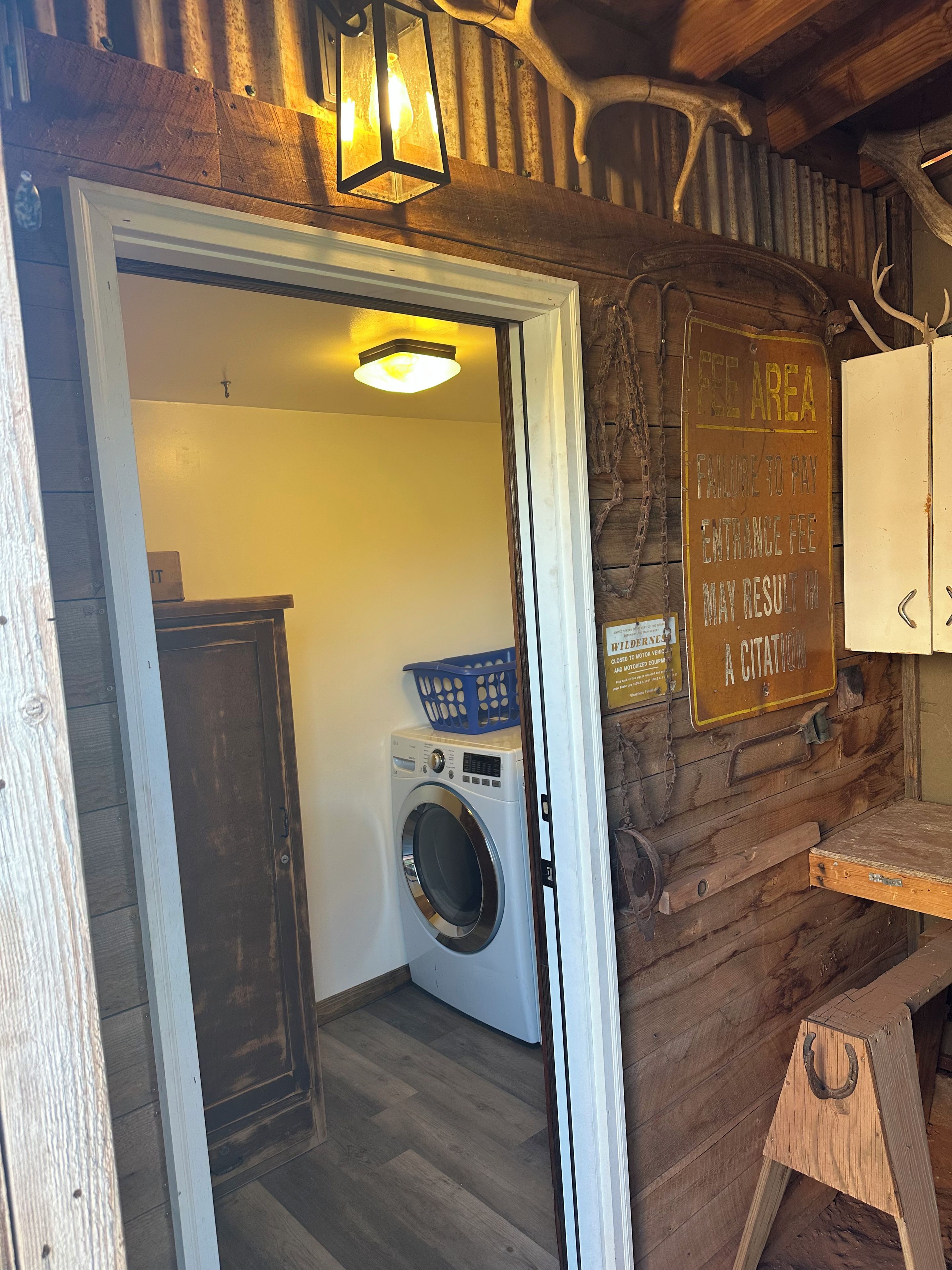A rustic interior with a wooden wall, a washing machine, and a sign indicating a fee area.