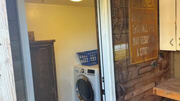 A rustic interior with a wooden wall, a washing machine, and a sign indicating a fee area.