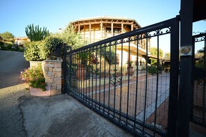 A gated entrance with a stone planter and potted plants.