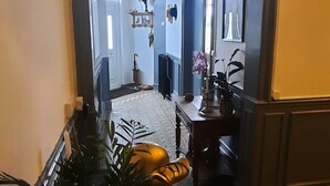 A hallway with an arched doorway leading to a room. There is a potted plant in the foreground, a patterned carpet, and a small table with a vase. - Villa BeauSejour in the heart of the countryside  (Baives)