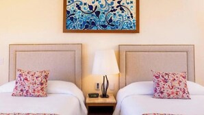 Une chambre d’hôtel avec deux lits, une table de chevet avec une lampe et un tableau accroché au mur.