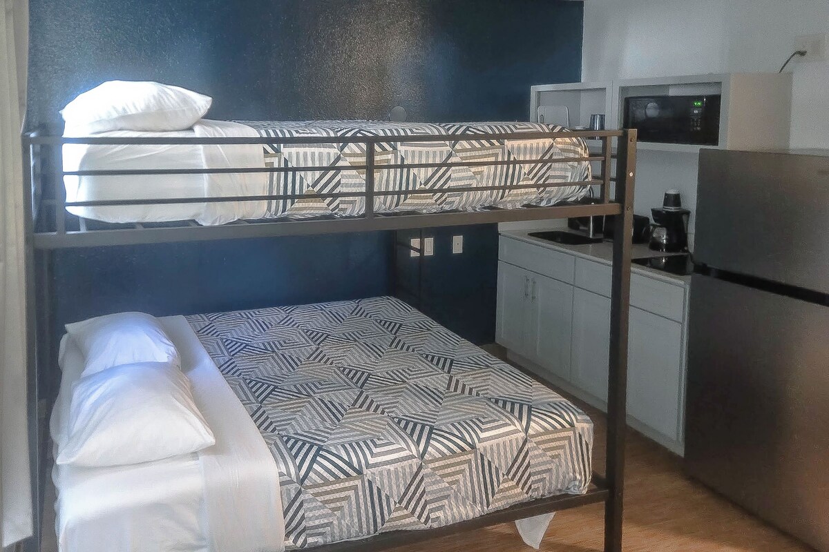 Un letto a castello con biancheria decorata, angolo cottura completo di frigorifero e microonde.