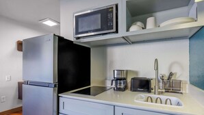 A compact kitchen with a refrigerator, microwave, toaster, coffee maker, and a sink with a faucet. - Studio 6 Seattle, WA Sea-tac Airport South (SeaTac)