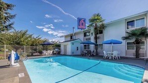 A hotel with a swimming pool, outdoor seating, and a sign indicating it is a '6 Motel & Studio'. - Studio 6 Seattle, WA Sea-tac Airport South (SeaTac)