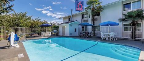 Un hotel con piscina, asientos al aire libre y un letrero que indica que es el '6 Motel & Studio'.
