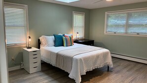 Un dormitorio con cama, mesitas de noche, escritorio y tragaluz.