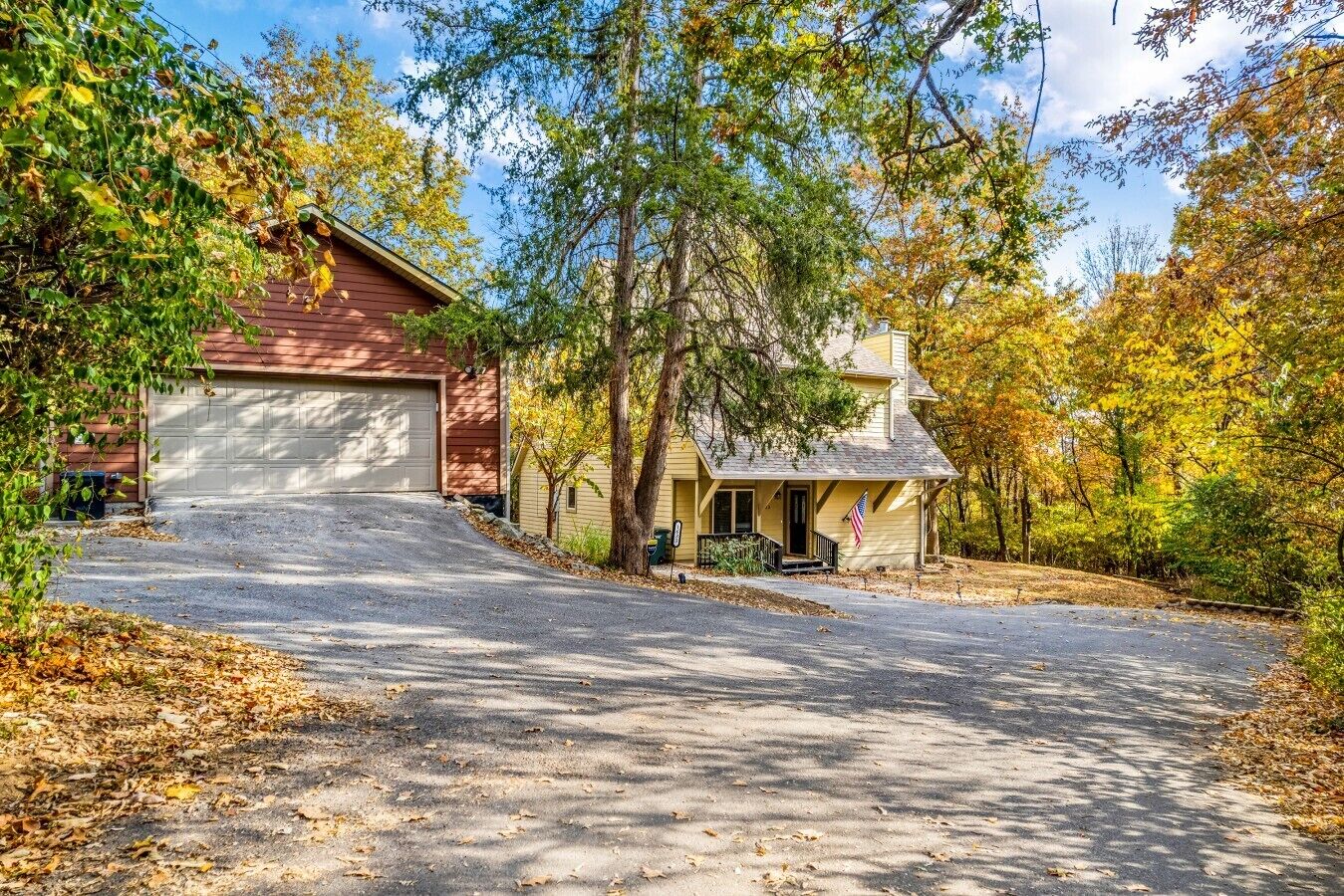 A two-story house with a garage, surrounded by trees and a driveway.