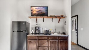 Eine kompakte Küche mit integriertem Kühlschrank, einer Kaffeemaschine und einem Spülbecken.