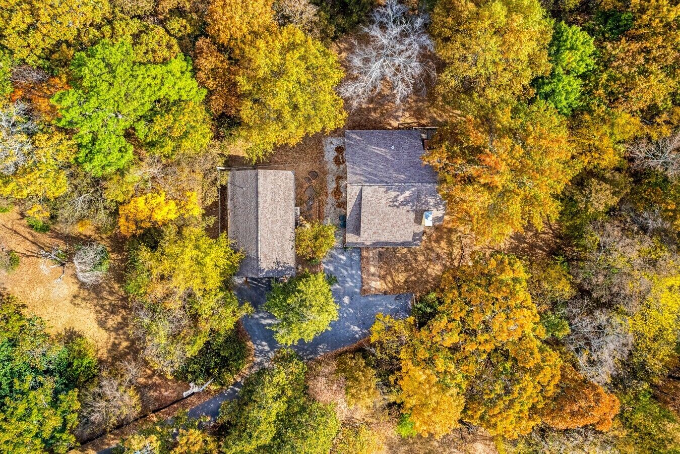 An aerial view of a property with a two-story building, a driveway, and surrounding trees.