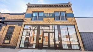 Un hôtel appelé «The Blue Jay Hotel & Suites», avec une façade en briques, de grandes fenêtres et une porte noire.