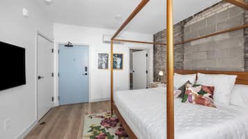 Un dormitorio moderno con una cama con dosel, suelo de madera y una pared de ladrillo decorativa.