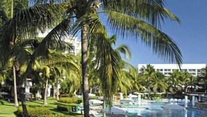 A resort with a swimming pool, palm trees, and a building in the background.