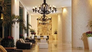 A spacious lobby with a chandelier, seating area, and a reception desk.