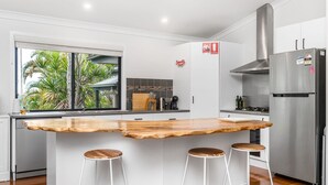 A modern kitchen with a wooden island, stainless steel appliances, and a view of tropical foliage. - Serenity Now - New Property, minutes from the beach and village, yet so peaceful and private (Lennox Head)
