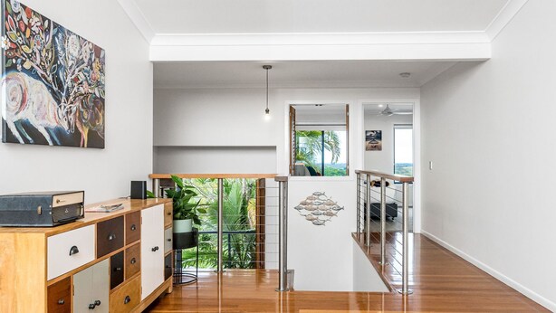 A modern interior with a wooden floor, a desk with a vintage radio, a potted plant, and a view of greenery through a glass door. - Serenity Now - New Property, minutes from the beach and village, yet so peaceful and private (Lennox Head)