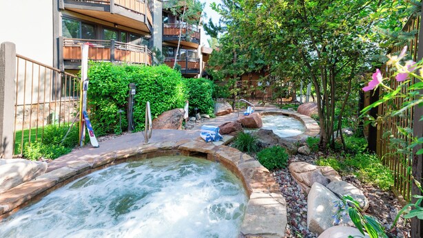 Un área de spa con jacuzzis rodeada de jardines naturales y una valla de madera.