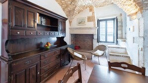 Une cuisine rustique avec un plafond en pierre, des meubles en bois, des chaises en osier et une cheminée.