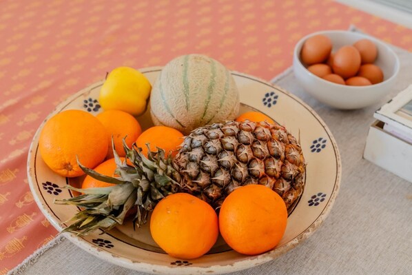 A plate with oranges, a lemon, a pineapple, and a melon.