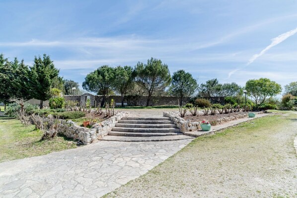 Un sendero de piedra que conduce a un edificio, rodeado de follaje y árboles.