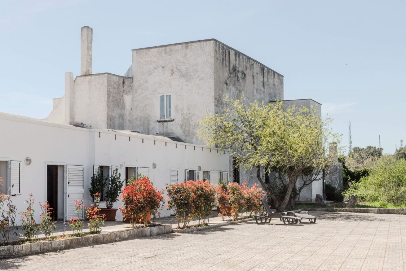 Un patio con un edificio, plantas en macetas y un banco.