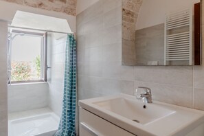 A bathroom with a shower, a sink, and a mirror.
