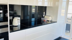 Una cocina moderna con armarios blancos, encimeras negras y horno integrado.