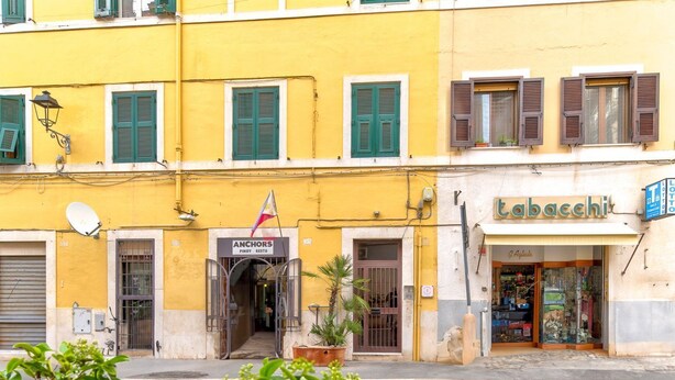 A yellow building with a restaurant named 'ANCHORS' and a tobacchi shop. - La Posada by Rentbeat (Civitavecchia)