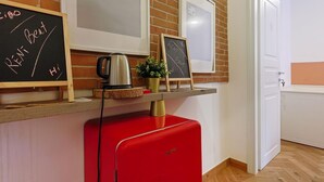 Une petite cuisine équipée d’un réfrigérateur rouge, d’une machine à café et de tableaux noirs sur lesquels on peut écrire.