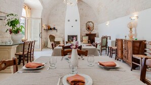 A dining area with tables set for four, a chandelier, and a fireplace. - Masseria Carbonico delle Lamie - Suite by Rentbeat (Martina Franca)