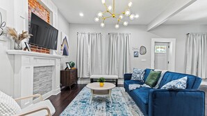 Ein modernes Wohnzimmer mit einem blauen Sofa, einem runden Couchtisch und einem Kamin.