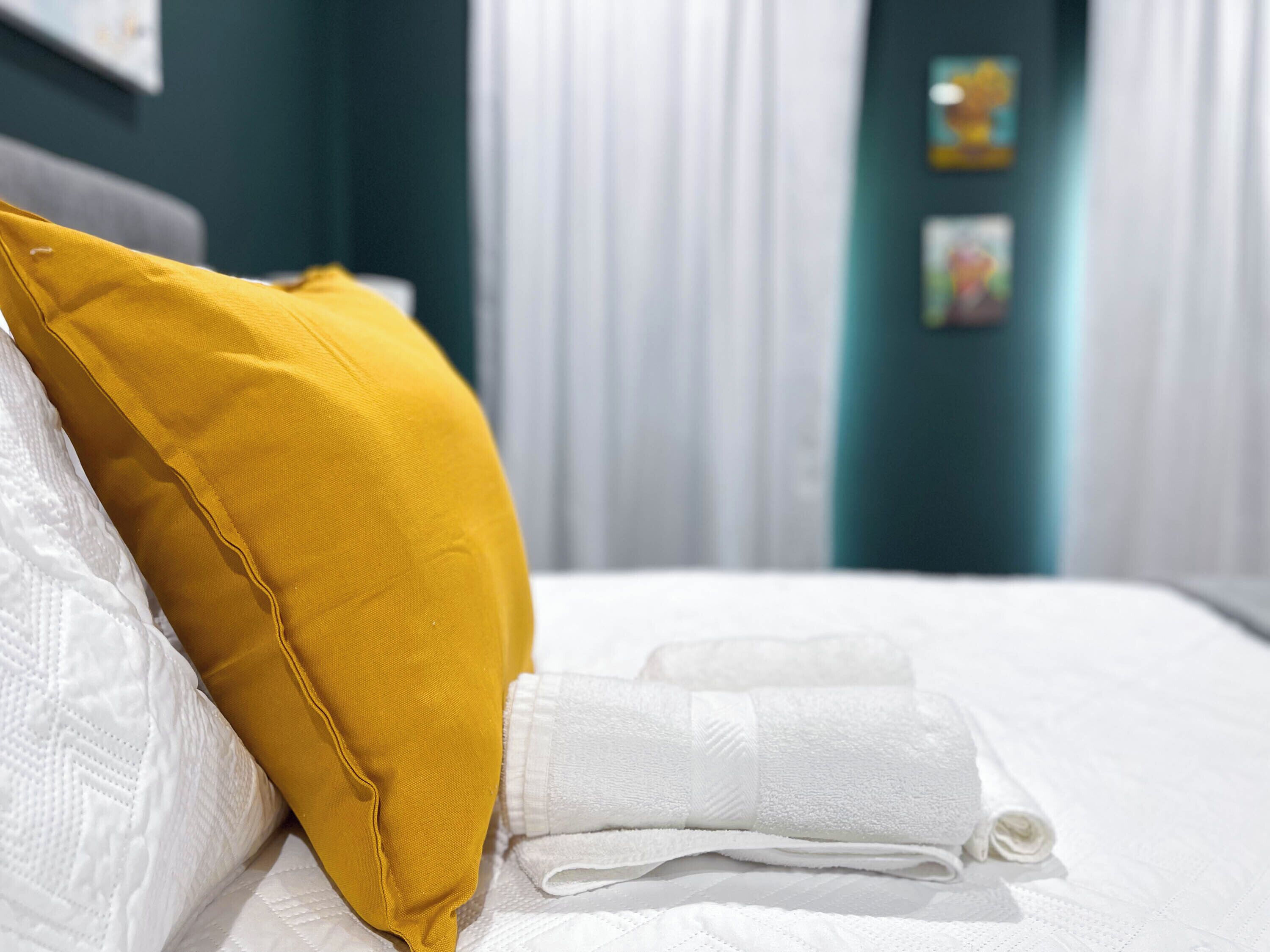 Una cama bien hecha con una almohada blanca y una toalla blanca doblada.