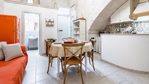 A compact living space with a dining area, kitchenette, and a visible bathroom. - Portici Guest House by Rentbeat (Fasano)