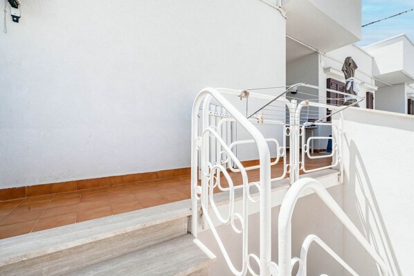Un escalier en métal blanc, doté d’une rampe, mène à un balcon.