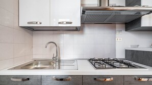 A modern kitchen with a stainless steel sink, a gas stove, and grey cabinets. - Residence Anna by Rentbeat (Villanova)