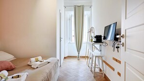 A hotel room with a bed, a desk, a television, and a shower curtain. - La Posada - Camera 2 by Rentbeat (Civitavecchia)