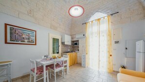 A compact living space with a dining area, kitchen, and a single bed. - Salentina by Rentbeat (Ostuni)