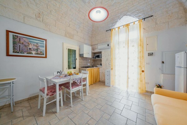 A compact living space with a dining area, kitchen, and a single bed.