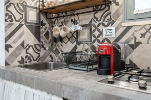 Cucina dal design moderno, con lavello in acciaio inossidabile, macchina da caffè e piano cottura a gas.
