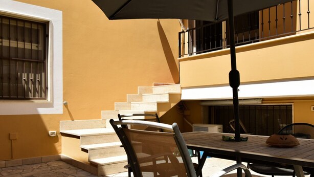 A patio with a table, chairs, and a large umbrella.