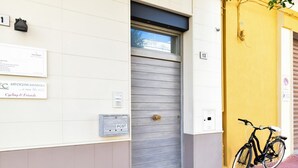 A building with a closed metal door, a bicycle parked outside, and a mailbox on the wall.