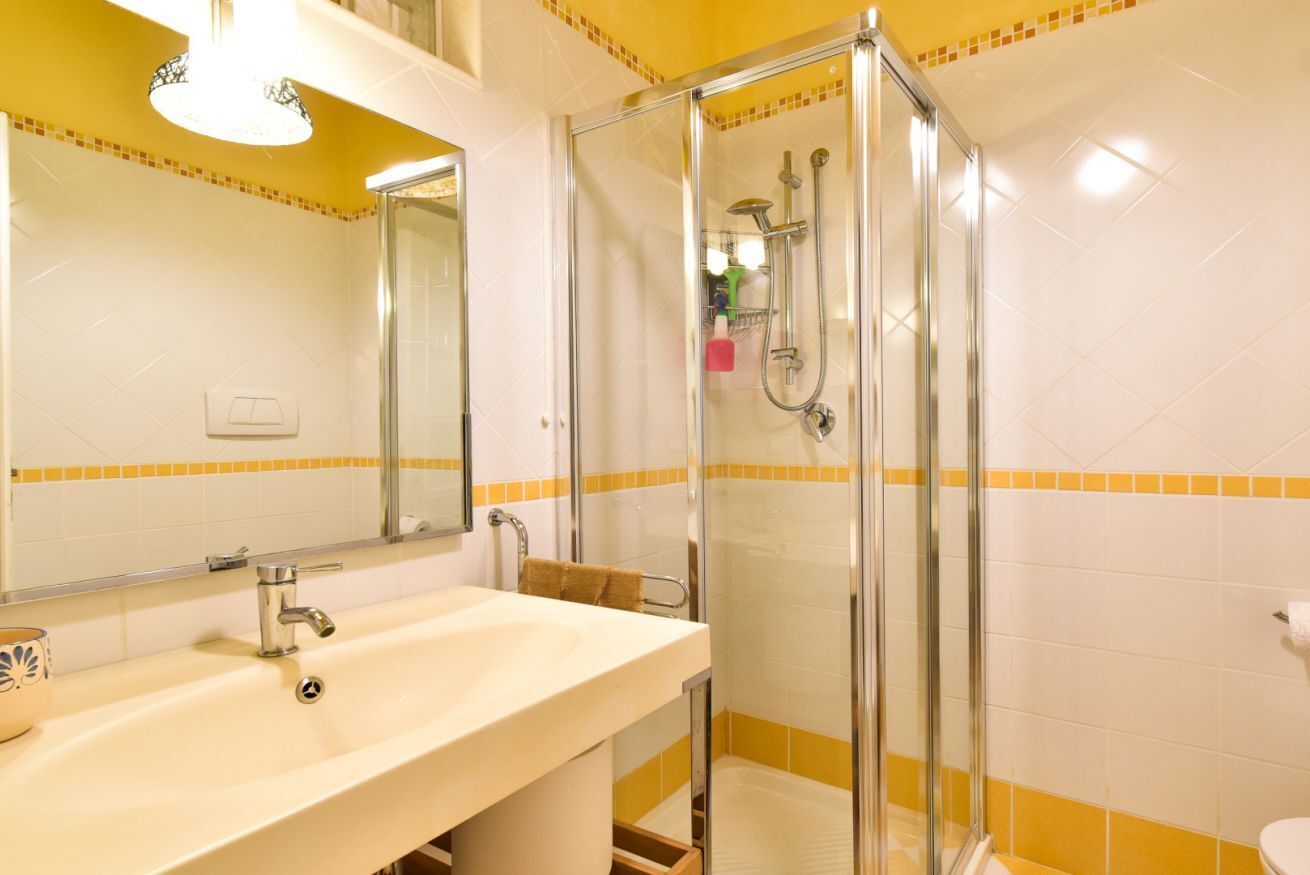 A bathroom with a glass-enclosed shower, a sink, and a mirror.