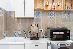 A kitchen with a coffee machine, microwave, and washing machine.