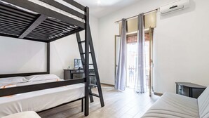 A room with bunk beds, a desk, a chair, a sofa, and an air conditioning unit. - Street View Apartment by Rentbeat (Bari)