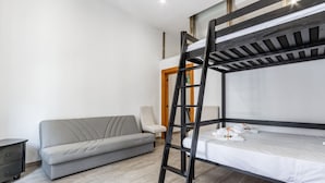 A bunk bed with a ladder, a grey sofa, a small table, and a wooden door. - Street View Apartment by Rentbeat (Bari)