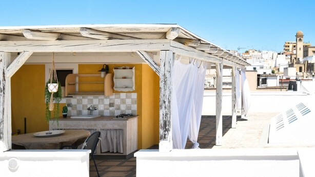Cocina en la azotea con una pared amarilla, un techo blanco y vista a la ciudad.