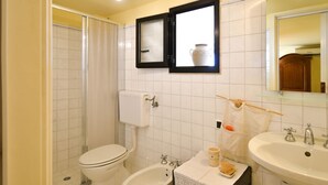 Un baño con inodoro, bidé, lavabo y un espejo con gabinete superior.