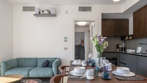 En moderne stue med spiseplads, sofa og køkken.