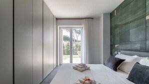 Et moderne hotelværelse med en stor seng, udsigt gennem en glasdør og en grøn accentvæg.