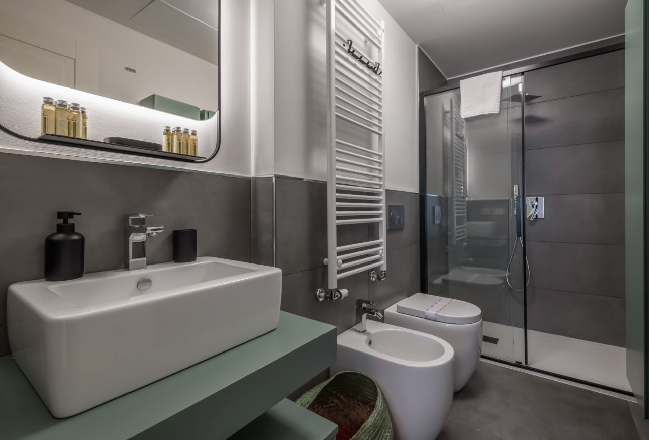A modern bathroom with a large bathtub, a separate bidet, a glass shower enclosure, and a towel rack.