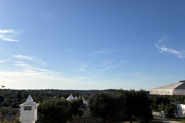 Un paysage rural avec un bâtiment blanc, une petite tour et un ciel bleu dégagé.